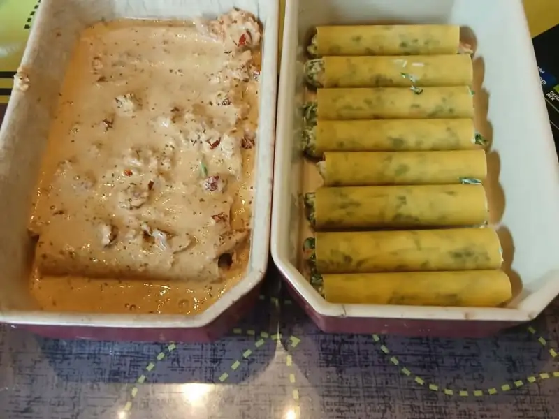 Cannelloni mit Spinat und Ricotta nebeneinander in einer Form, daneben eine zweite Form mit Lachs-Sahnesoße und getrockneten Tomaten