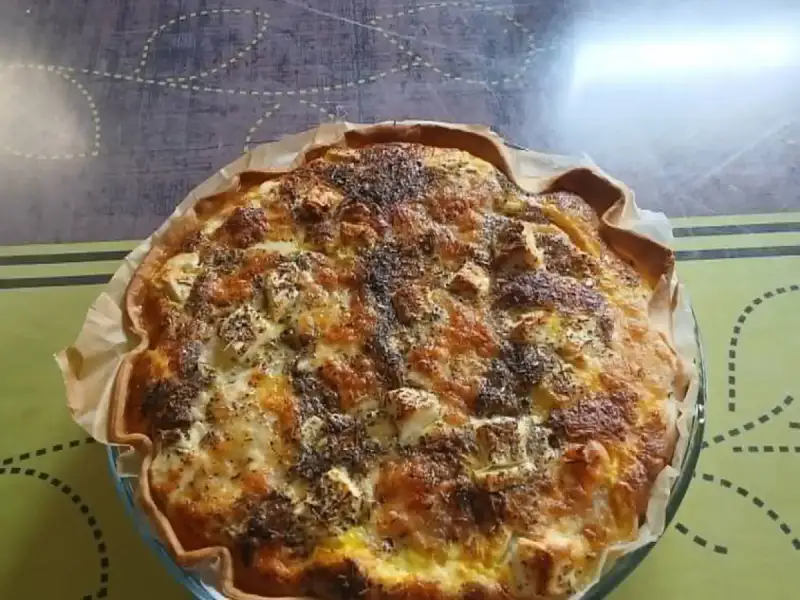 Goldbraun gebackene Quiche mit Hähnchen und Feta, mit Kräutern der Provence bestreut, in ihrer Glasform