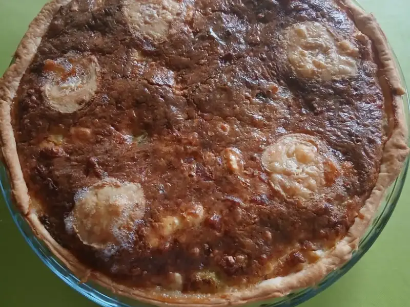 Schön goldbraune Resteverwertungs-Quiche mit Ziegenkäsescheiben in einer Glasform