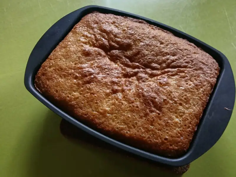 Goldbrauner, hoch aufgegangener Vierviertelkuchen mit Obst in einer rechteckigen Form